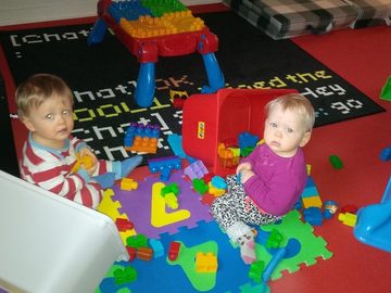 A toddler playing with building blocks on the mat at Kidz R Os