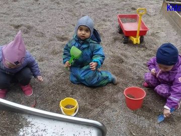 A child in a snowsuit playing in the sand outdoors at Kidz R Os